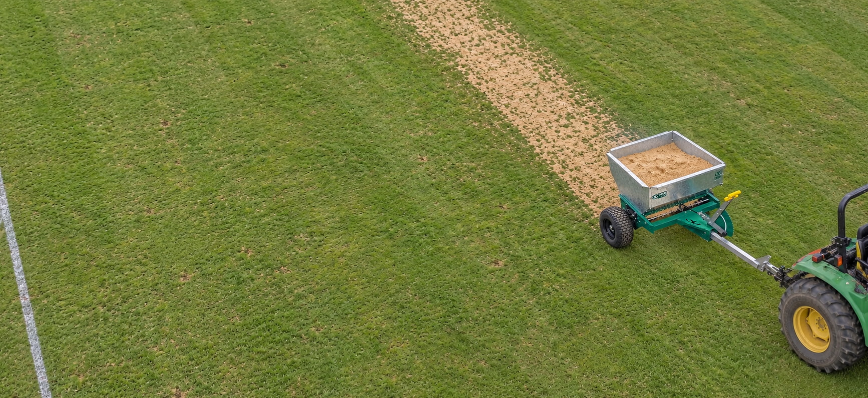 Arenadora Yafun trabajando sobre el césped de un campo deportivo, vista aérea